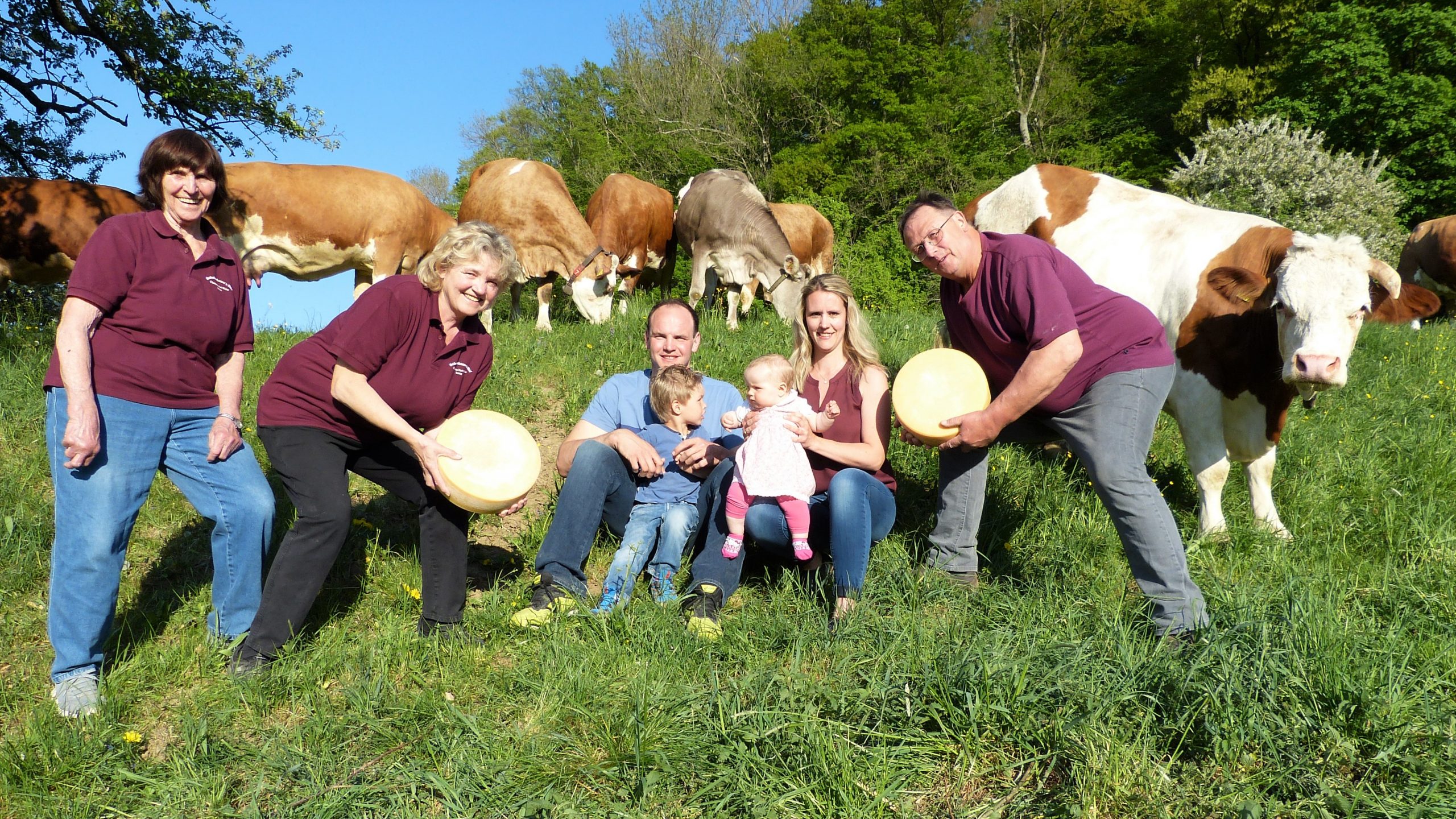 Schulzebauer´s Hof Familie mit Käse in der Hand und Kühen im Hintergrund